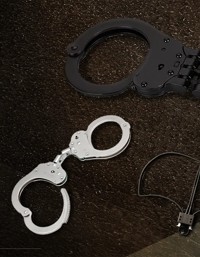 A promotional product layout showing a pair of black handcuffs, a pair of silver handcuffs, a black wire lock pick set, and a black pick tool on a dark textured background with Thai marketing text and small icons.